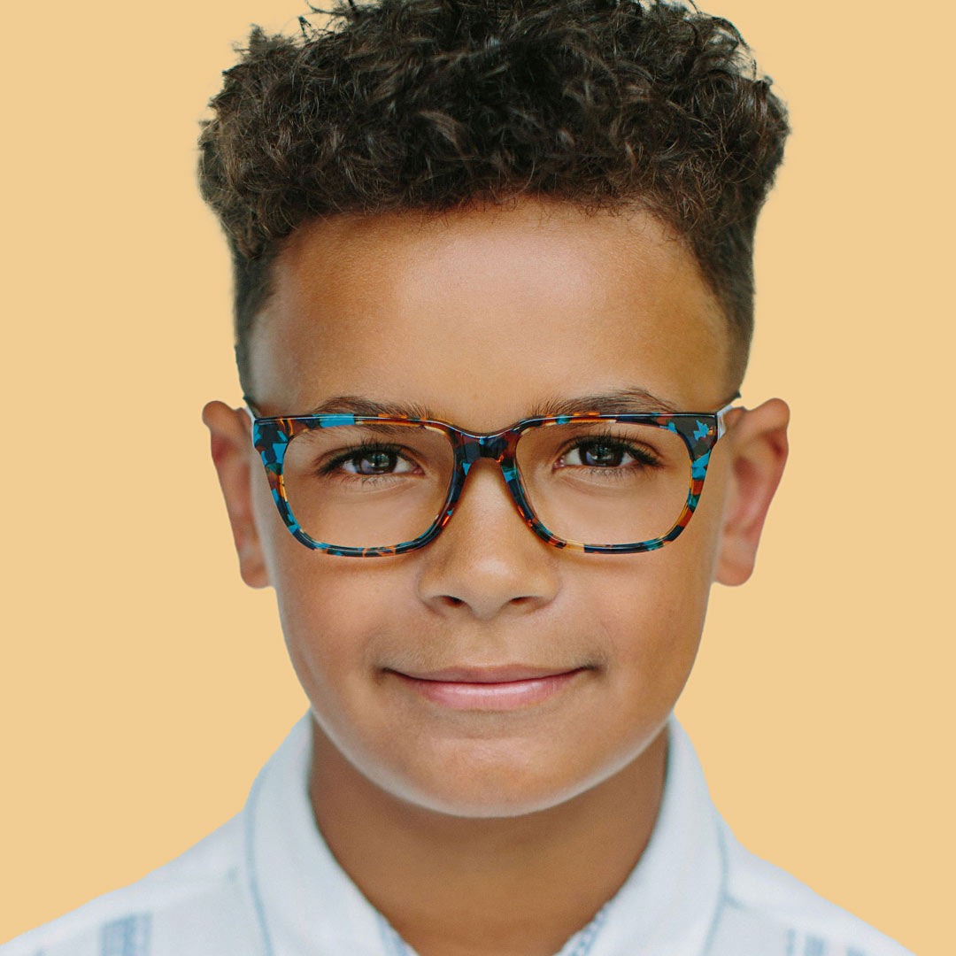 Boy wearing turquoise tortoise rectangle glasses and a white shirt