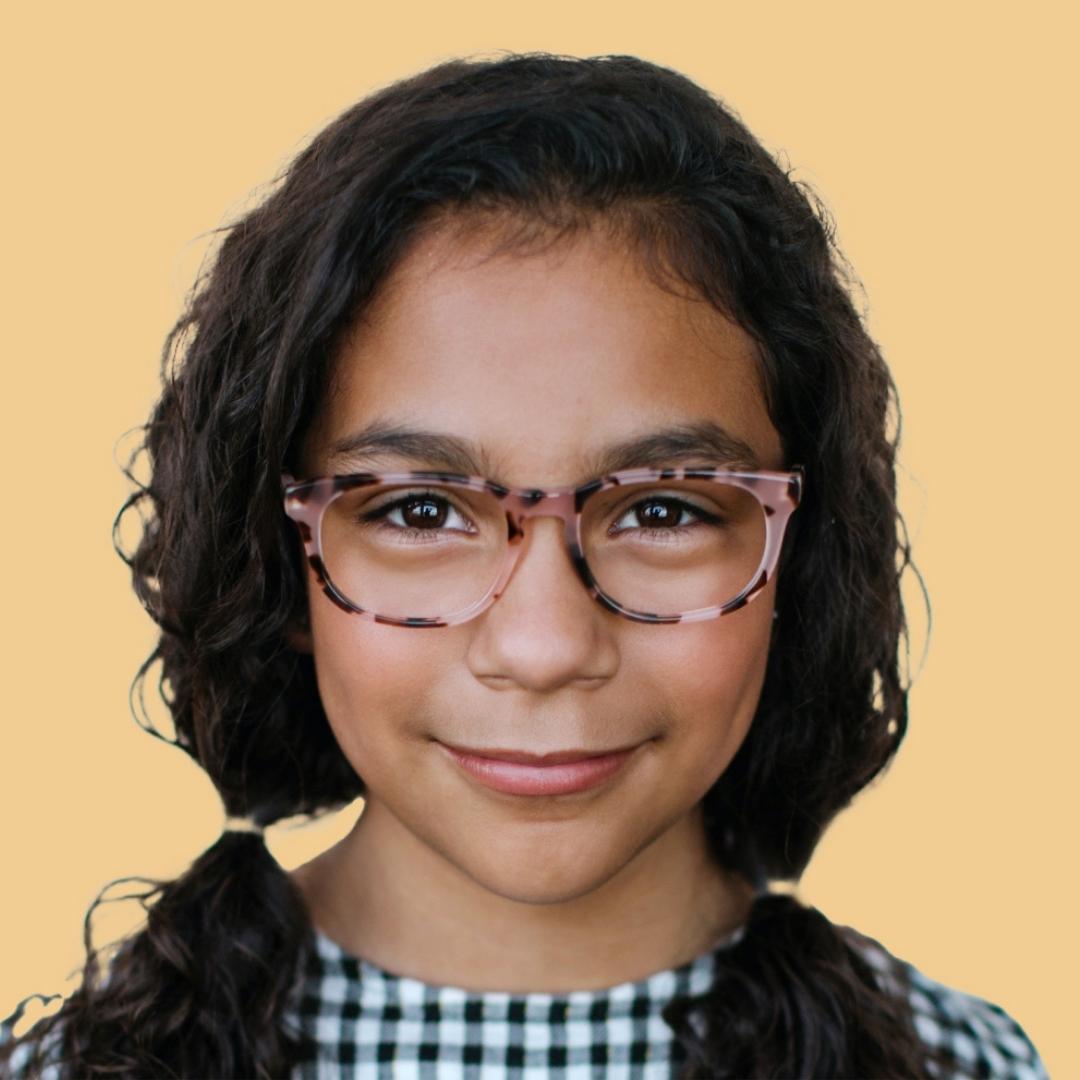 Little girl wearing Candy Tortoise glasses in pigtails and checkered shirt 